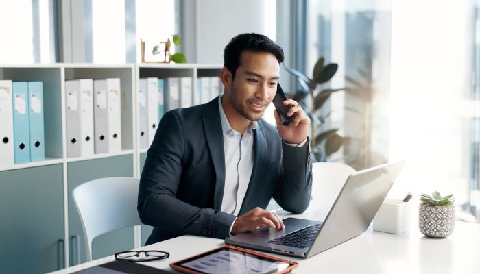 Person talking on a cellphone while sitting at a computer desk